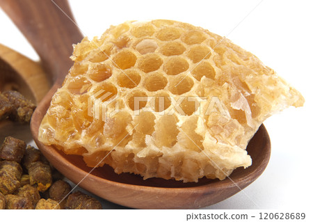 A detailed view of a honeycomb piece resting on a wooden spoon A detailed view of a honeycomb piece resting on a wooden spoon 120628689
