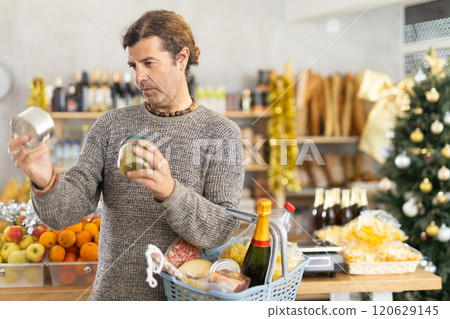 Man choosing preserves for festive grocery basket on Christmas Eve 120629145