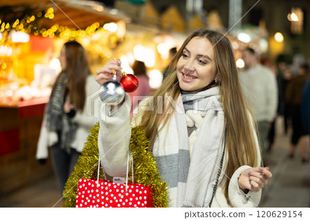 Young girl bought New Years balls toys and tinsel and in shopping pavilion and admires her purchase 120629154
