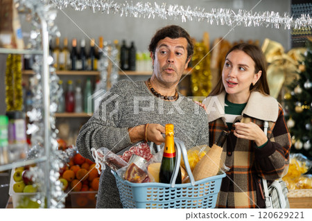 Cheerful couple shopping for Christmas dinner wine and goodies 120629221