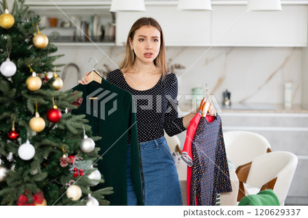 Upset indecisive woman can choose dress in her wardrobe for Christmas celebration Upset indecisive woman can choose dress in her wardrobe for Christmas celebration 120629337