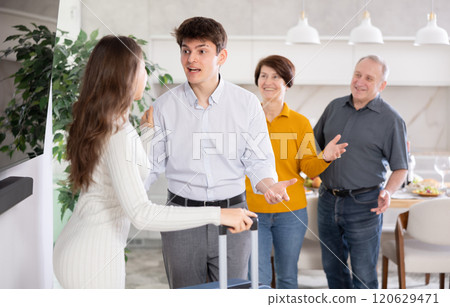 Positive young girl with suitcase coming to visit relatives. Family meeting Positive young girl with suitcase coming to visit relatives. Family meeting 120629471