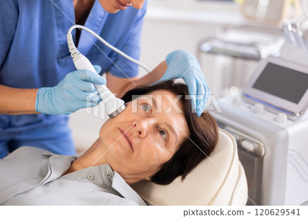 Elderly woman undergoing cosmetic high frequency ultrasound facial treatment Elderly woman undergoing cosmetic high frequency ultrasound facial treatment 120629541