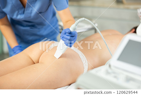 Adult female cosmetologist performs scrubbing procedure on butt of young woman 120629544