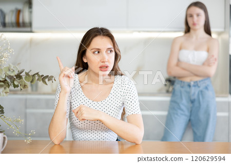 Two young women quarrel in kitchen at home Two young women quarrel in kitchen at home 120629594