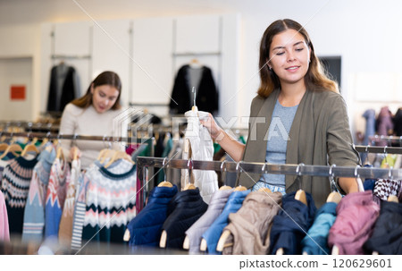 Young woman choosing insulated vest in store 120629601