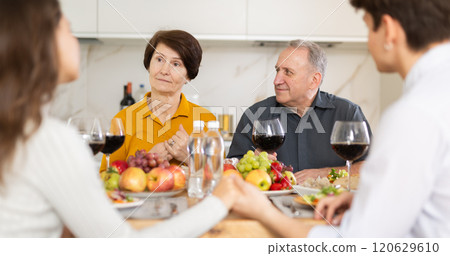 Elderly parents enjoying family dinner with young adult children 120629610