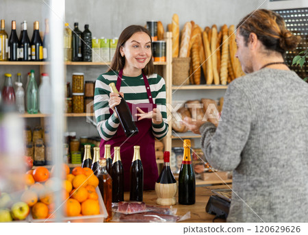 Female seller offers man to buy alcohol in the supermarket Female seller offers man to buy alcohol in the supermarket 120629626