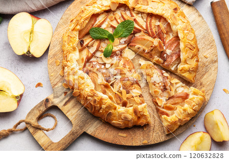 Delicious homemade apple galette with almond flakes and fresh mint on rustic wooden board 120632828