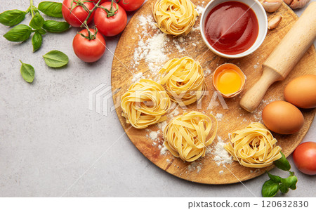 Fresh tagliatelle pasta nests with tomatoes, basil, eggs, flour and tomato sauce on wooden board Fresh tagliatelle pasta nests with tomatoes, basil, eggs, flour and tomato sauce on wooden board 120632830