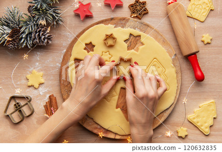 Woman making christmas cookies using star shaped cutters on wooden board 120632835