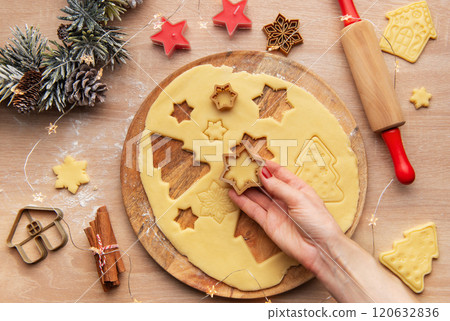 Woman making christmas cookies using star shaped cutters on wooden board Woman making christmas cookies using star shaped cutters on wooden board 120632836