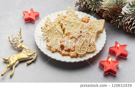 Christmas gingerbread cookies decorated with icing on white plate with festive decorations 120632839