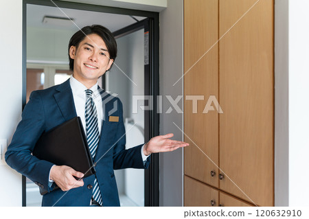 A male salesman from a house manufacturer showing off storage shelves in a model house/housing exhibition hall 120632910