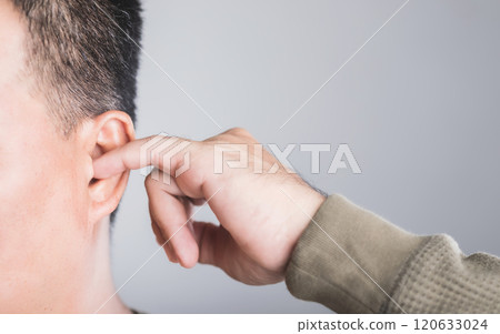 Close-up of a man using his finger to scratch inside his ear, highlighting the risks of ear irritation and injury from ear picking. This image emphasizes the importance of safe ear care practices Close-up of a man using his finger to scratch inside his ear, highlighting the risks of ear irritation and injury from ear picking. This image emphasizes the importance of safe ear care practices 120633024