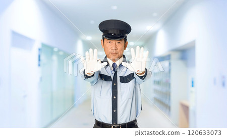 A male security guard stops someone in the building's corridor A male security guard stops someone in the building's corridor 120633073