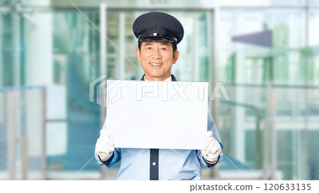 A male security guard showing a message board at the building entrance 120633135