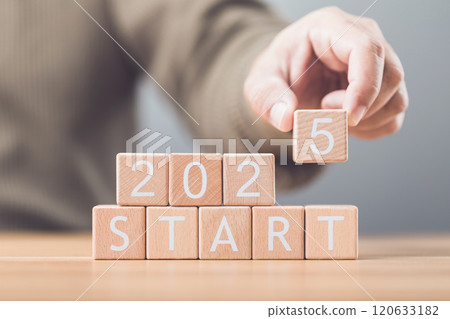 Businessman arranges wooden blocks spelling out 'START 2025' on a table, symbolizing the beginning of new goals and ventures for the upcoming year. Image reflects motivation and forward planning Businessman arranges wooden blocks spelling out 'START 2025' on a table, symbolizing the beginning of new goals and ventures for the upcoming year. Image reflects motivation and forward planning 120633182