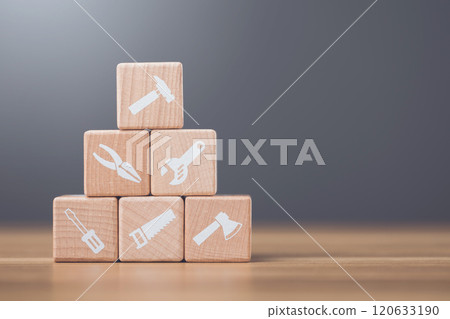 Wooden blocks marked with tool symbols represent home repair and maintenance essentials. This image highlights the importance of upkeep and the tools needed for home improvement projects 120633190