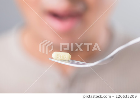 Man prepares to take medication, with a yellow pill placed on a fork. This image symbolizes the act of taking medicine and highlights health and wellness practices Man prepares to take medication, with a yellow pill placed on a fork. This image symbolizes the act of taking medicine and highlights health and wellness practices 120633209