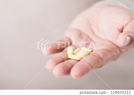 A man holds several yellow pills in his hand, highlighting the risk of overdosing beyond prescribed limits. This image emphasizes the importance of following medical advice for safe medication use 120633212