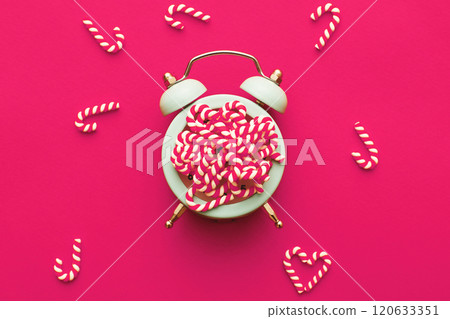 Christmas background with candy canes on alarm clock on pink background 120633351