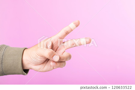 Hand with bandages or plaster on the index and middle fingers forming a 'V' sign, symbolizing resilience and the ability to keep working and going despite minor injuries 120633522