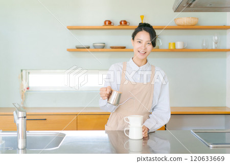 A woman in an apron standing in the kitchen 120633669