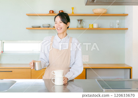 A woman in an apron standing in the kitchen 120633670