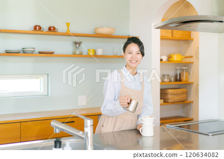 A woman in an apron standing in the kitchen 120634082