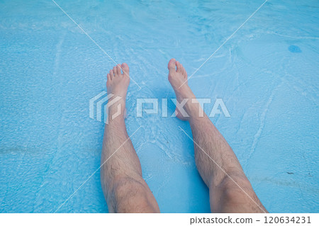 The legs of a man in his 40s sitting in the shallow waters of a wave pool 120634231
