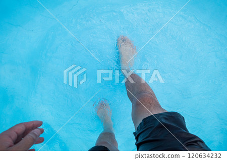 一名 40 多歲男子的腳在波浪池淺水中行走 120634232
