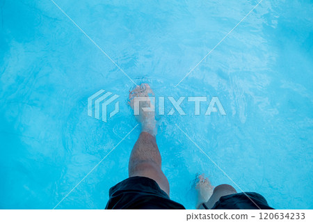 The legs of a man in his 40s walking through the shallow waters of a wave pool The legs of a man in his 40s walking through the shallow waters of a wave pool 120634233