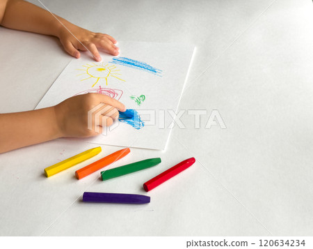 Child drawing with crayons on white paper creates colorful artwork Child drawing with crayons on white paper creates colorful artwork 120634234