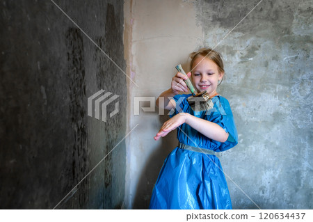 9-year-old girl in blue workwear priming a cement wall. Renovation concept. 9-year-old girl in blue workwear priming a cement wall. Renovation concept. 120634437