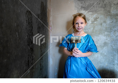 9-year-old girl in blue workwear priming a cement wall. Renovation concept. 9-year-old girl in blue workwear priming a cement wall. Renovation concept. 120634438