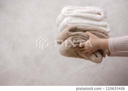 Little girl's hand holding a stack of soft towels Little girl's hand holding a stack of soft towels 120635486