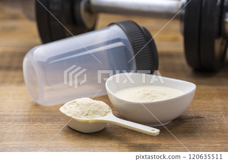 Protein, measuring spoon, shaker and dumbbells in preparation for muscle training 120635511