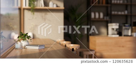 Side view of a long wooden table against the window in a cozy contemporary coffee shop. 120635628