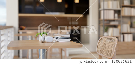 A table in a cozy contemporary cafe, the table features headphones, books, and a decorative plant. 120635631