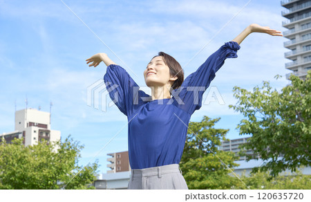 A woman taking a deep breath outside 120635720