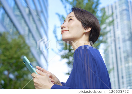 Woman in her 40s using a smartphone outdoors Woman in her 40s using a smartphone outdoors 120635732