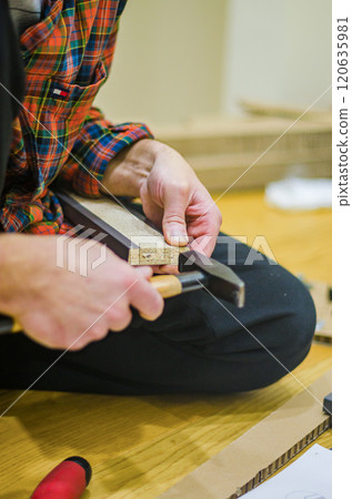 male holding hummer Assembly Instruction on Wooden Floor for DIY Furniture Setup. High quality photo male holding hummer Assembly Instruction on Wooden Floor for DIY Furniture Setup. High quality photo 120635981