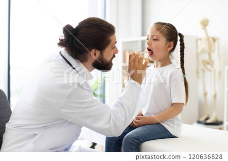 Caucasian doctor examines young girl's throat in medical clinic 120636828