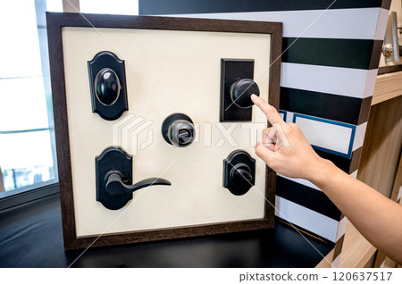 Designer hand pointing at vintage solid door knob on sample collection in hardware store 120637517