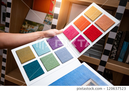 Designer hand holding carpet fabric swatch collection 120637523
