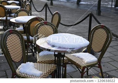 a snow-covered outdoor cafe setting, with empty chairs and tables dusted with fresh snow a snow-covered outdoor cafe setting, with empty chairs and tables dusted with fresh snow 120638022