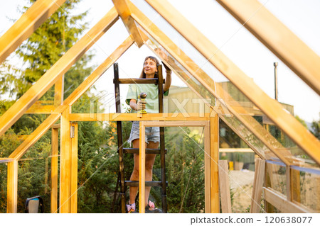 Female Carpenter Working on Greenhouse Female Carpenter Working on Greenhouse 120638077