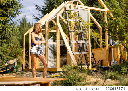 Woman building wooden greenhouse at backyard 120638174
