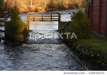 a small, rustic wooden bridge over a flowing river or stream a small, rustic wooden bridge over a flowing river or stream 120638247